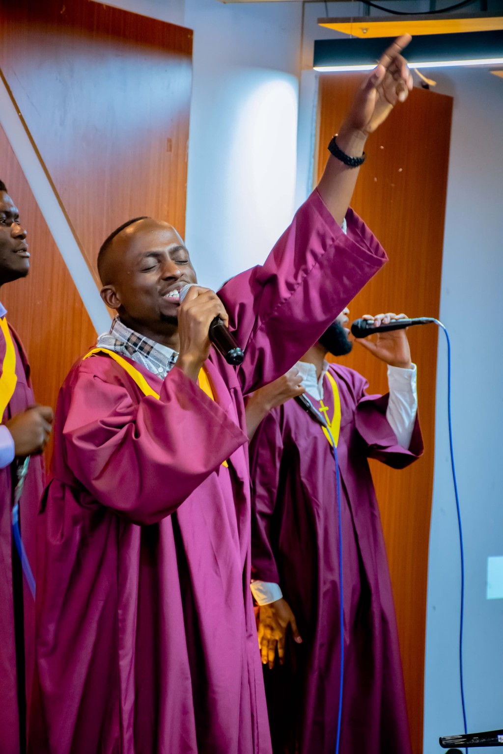 A choir singer holding a microphone and raising his hand during worship